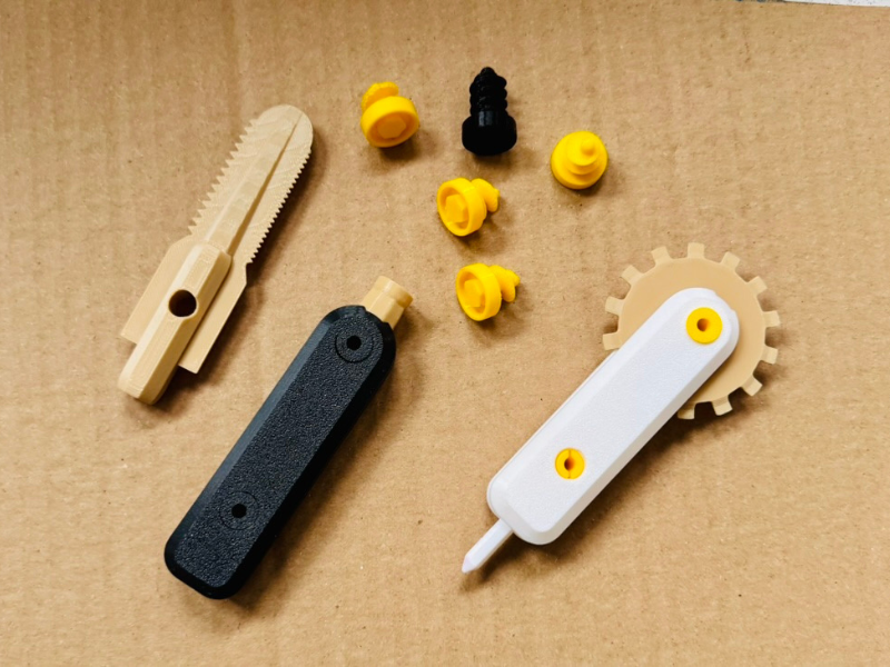 Karton-Werkzeug für Kinder aus dem 3D-Drucker 3D-gedruckte Werkzeuge für Kinder aus PLA, bestehend aus Säge, Schraubendreher und Cutter mit bunten Steckaufsätzen.