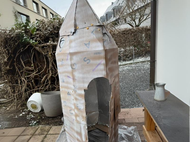 Große Rakete aus Karton mit ausgeschnittenem Eingang, gebaut mit 3D-gedruckten Werkzeugen für Kinder