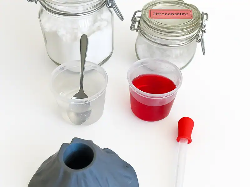 Materialien für das Vulkan Experiment mit Kindern: Zitronensäure, Backpulver, rote Flüssigkeit und ein 3D-gedruckter Vulkan.