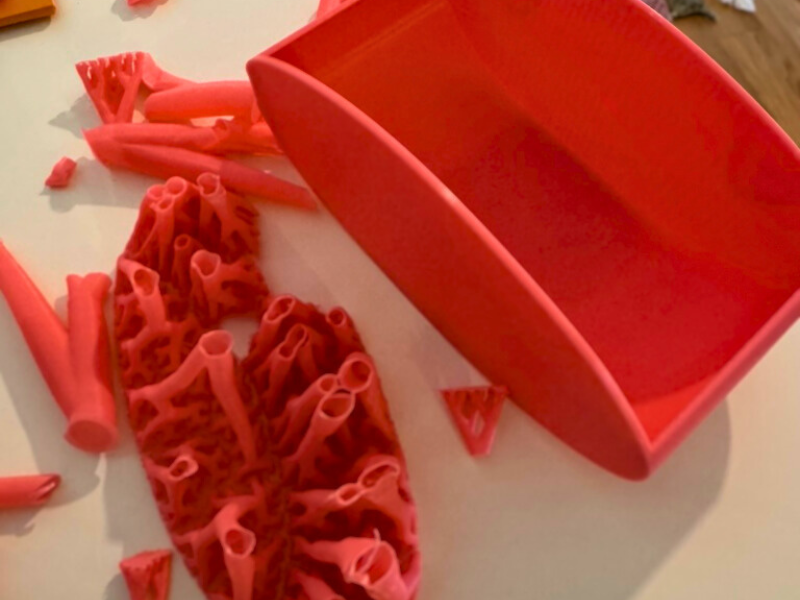 osa 3D-Druckteil nach Entfernen der Stützstrukturen, Reste der Supports liegen daneben.