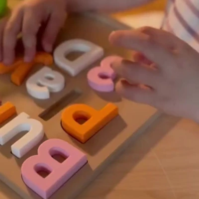 3D-Druck Namenspuzzle – Lernen mit Herz und Farbe Kinderhände spielen mit einem 3D-gedruckten Namenspuzzle in Pastellfarben – personalisiertes Lernspielzeug zum Buchstabenlernen und Spielen.