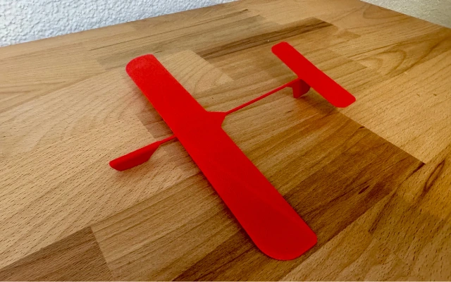 Rotes 3D-gedrucktes Flugzeug aus PLA auf Holztisch