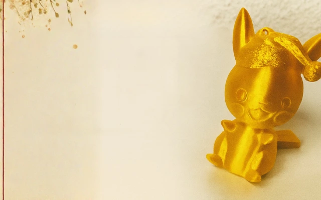 Goldene 3D-gedruckte Figur eines Pokémon mit Weihnachtsmütze auf hellem Untergrund