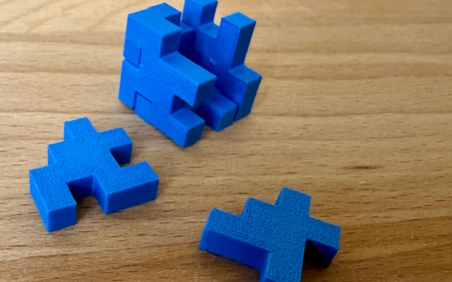 3D-gedrucktes Puzzle – kniffliges Steckspiel aus dem 3D-Drucker Blaues 3D-gedrucktes Steckpuzzle aus mehreren Teilen auf Holztisch
