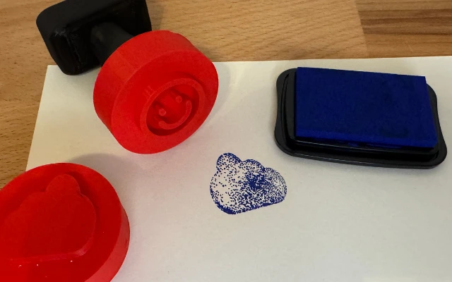 3D-gedruckte Stempel mit rotem Griff und blauer Stempelfarbe auf Papier