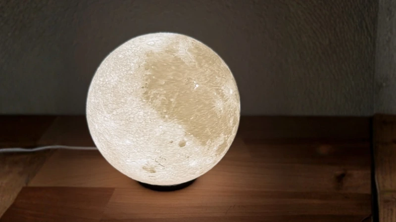 Mond-Nachtlicht 3D-gedrucktes Mond-Nachtlicht auf hellem Holztisch, sanft von innen beleuchtet mit LED-Teelicht – stimmungsvolles Kinderzimmerlicht aus dem Adventskalender 3D-Druck Teil 2 von BuildPlay3D.